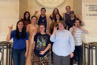 Longhorn TIES students stand on a staircase and smile with Hook 'Em hands.