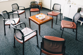 Seven chairs encircling a side table in an empty room.