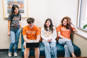 Four Longhorns looking at a computer together.