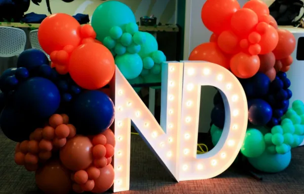 ND letters with orange, blue, and green balloons.