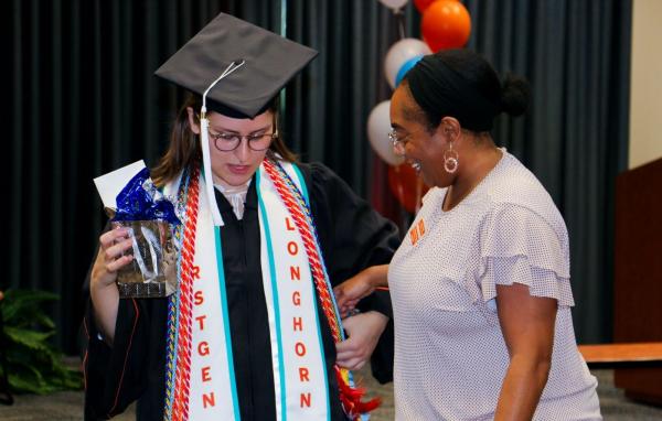 Longhorn TIES graduate wearing regalia and smiling Longhorn TIES coach.