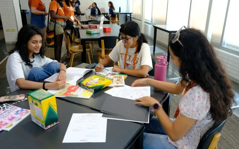 Three students color at an NDatUT event.