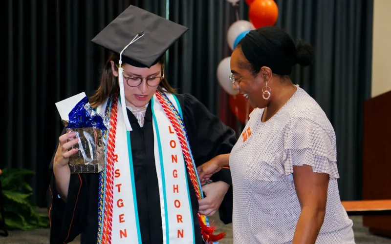 Longhorn TIES graduate wearing regalia and smiling Longhorn TIES coach.