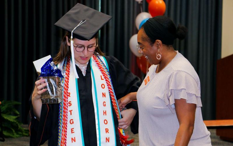 Longhorn TIES graduate wearing regalia and smiling Longhorn TIES coach.